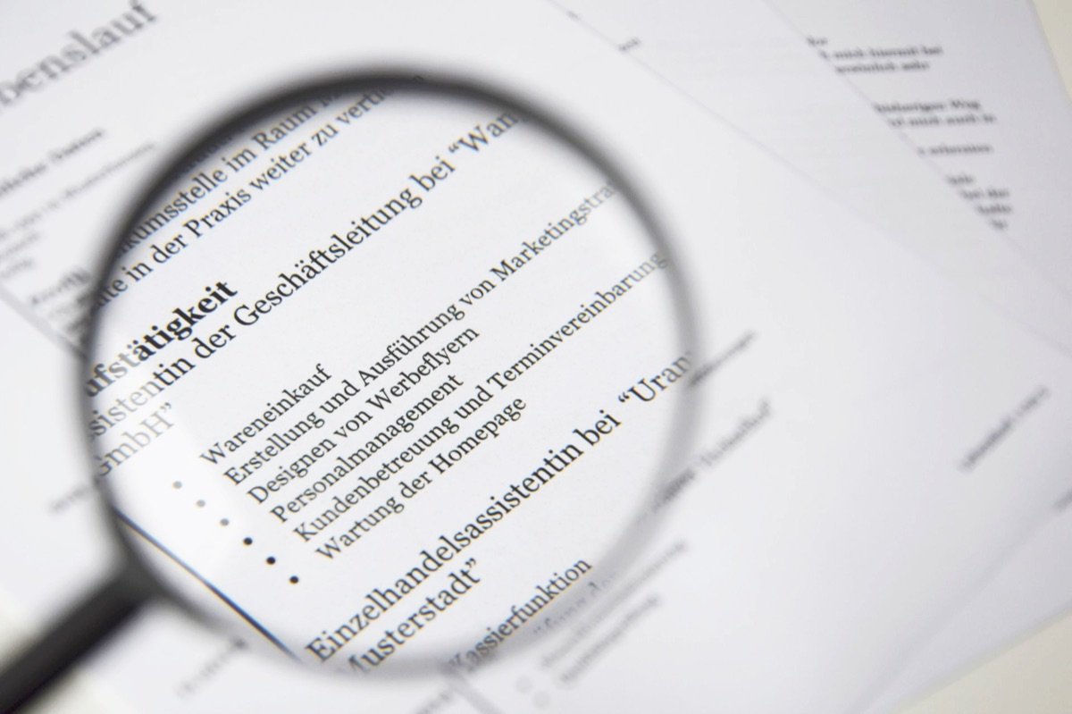 A magnifying glass over health insurance documents on a desk.