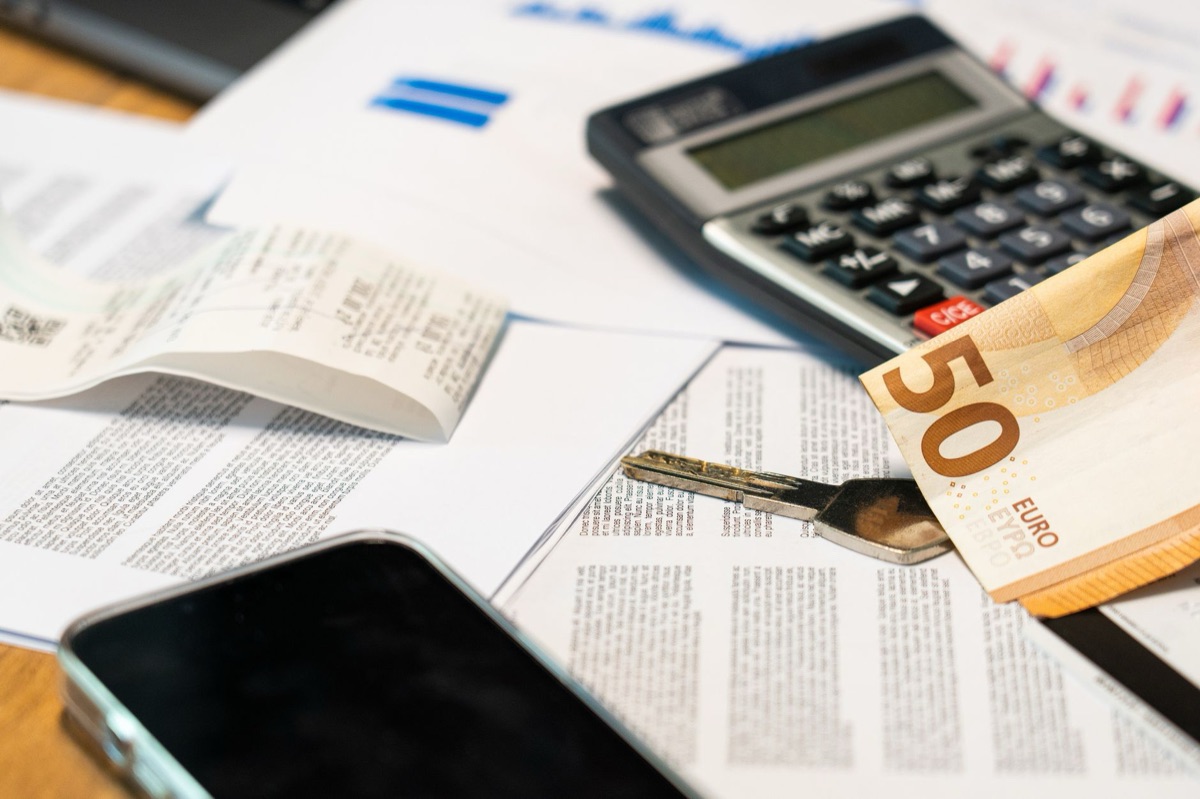 A calculator and coins next to a medical bill on a table.