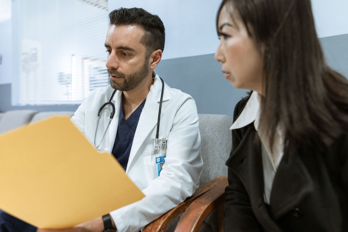 Médico con estetoscopio conversando con un paciente en una consulta clínica.