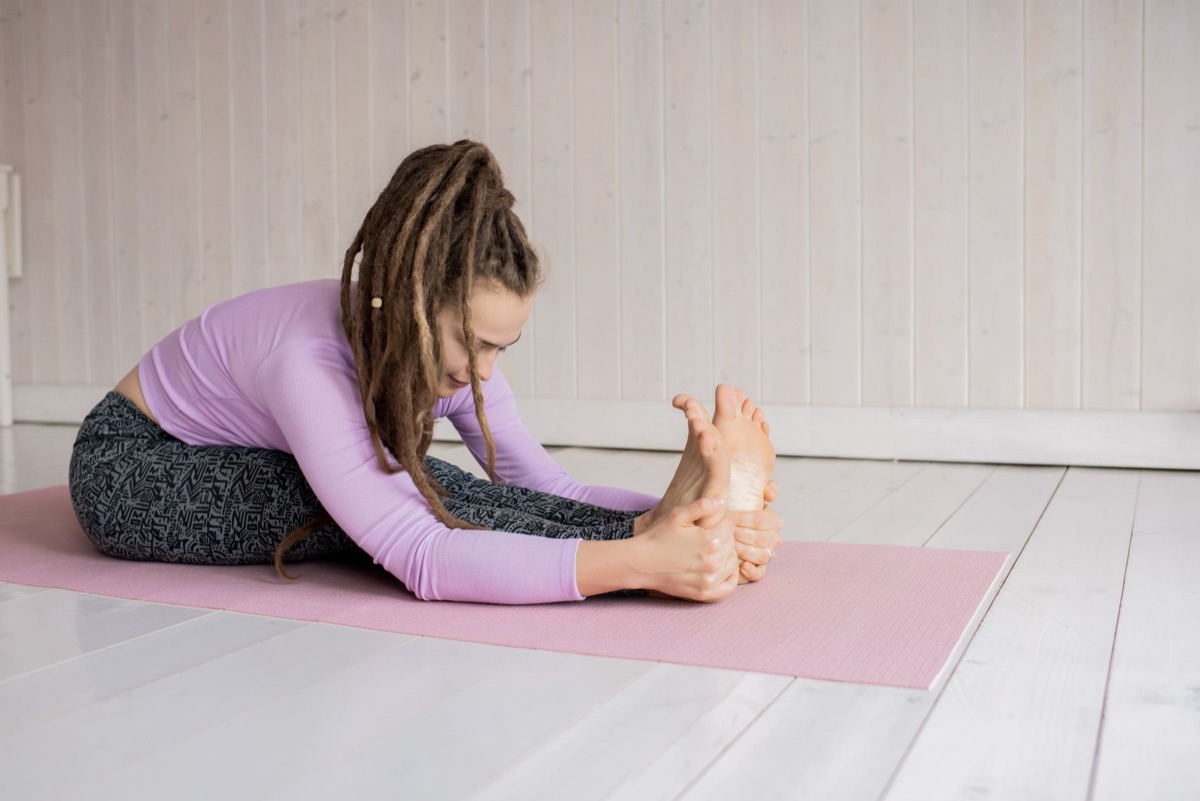 persoon die strectcheert op een yoga mat