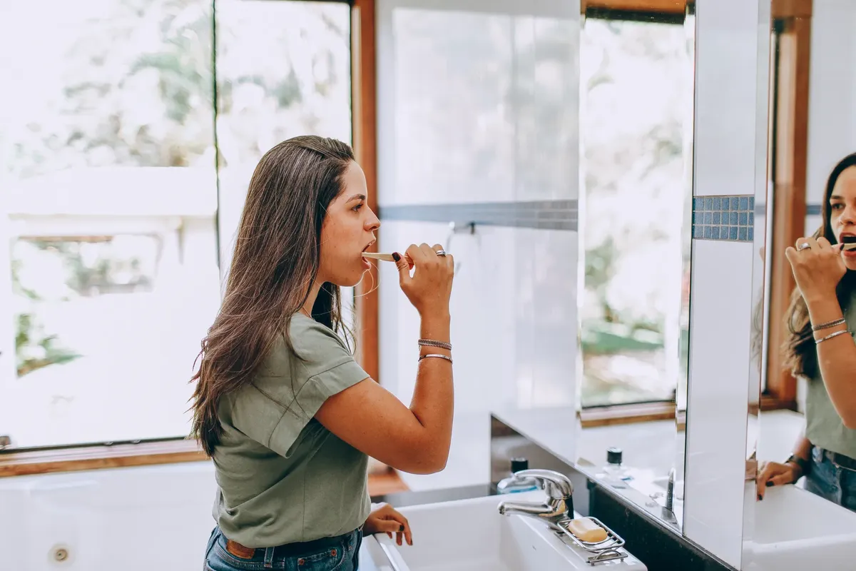 A woman enjoying her morning routine of brushing teeth in a bright, contemporary bathroom.